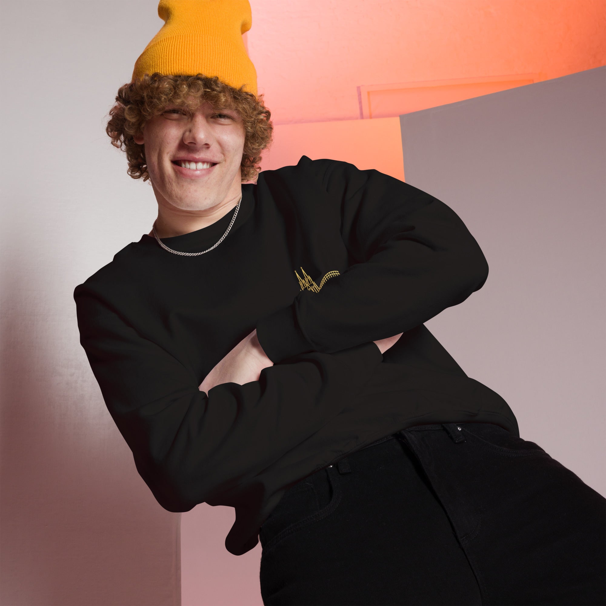Person wearing a black outfit with a yellow beanie against a colorful geometric background