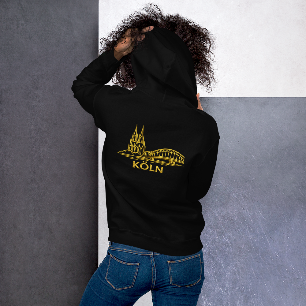 Person wearing a black hoodie with 'Köln' design on the back, standing against a gray and white wall.