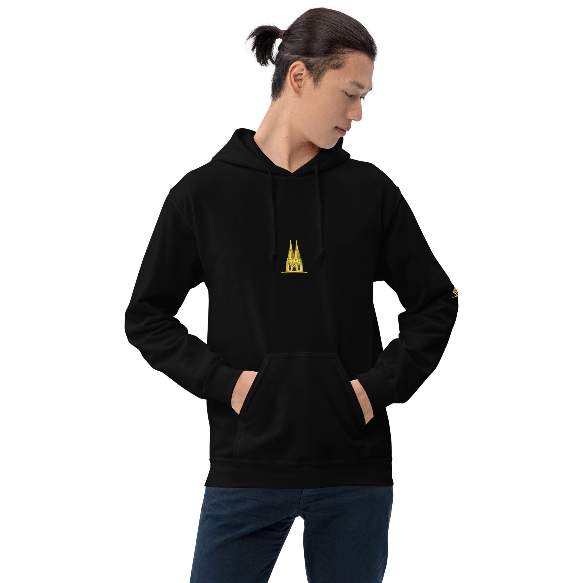 Person wearing a black hoodie with a Köln gold logo on a white background