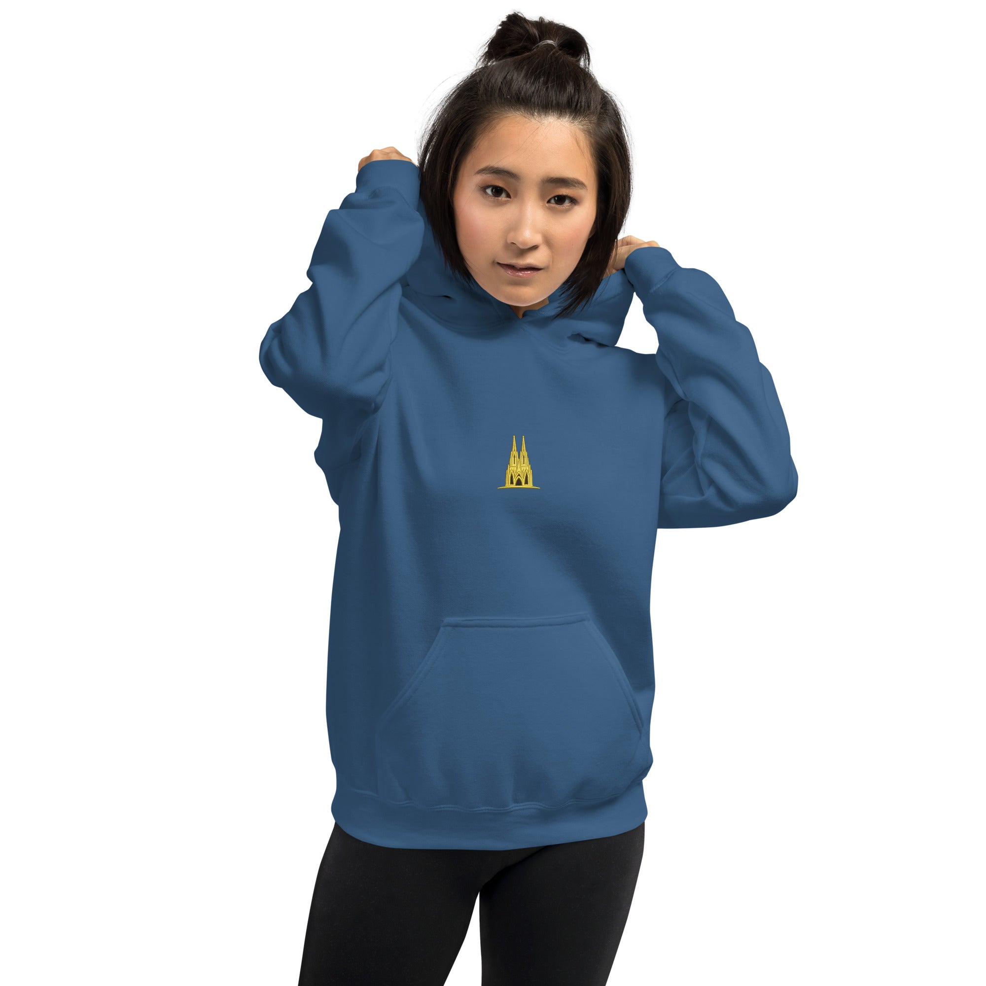 Person wearing a indigo blue hoodie with a small Köln yellow logo on a white background