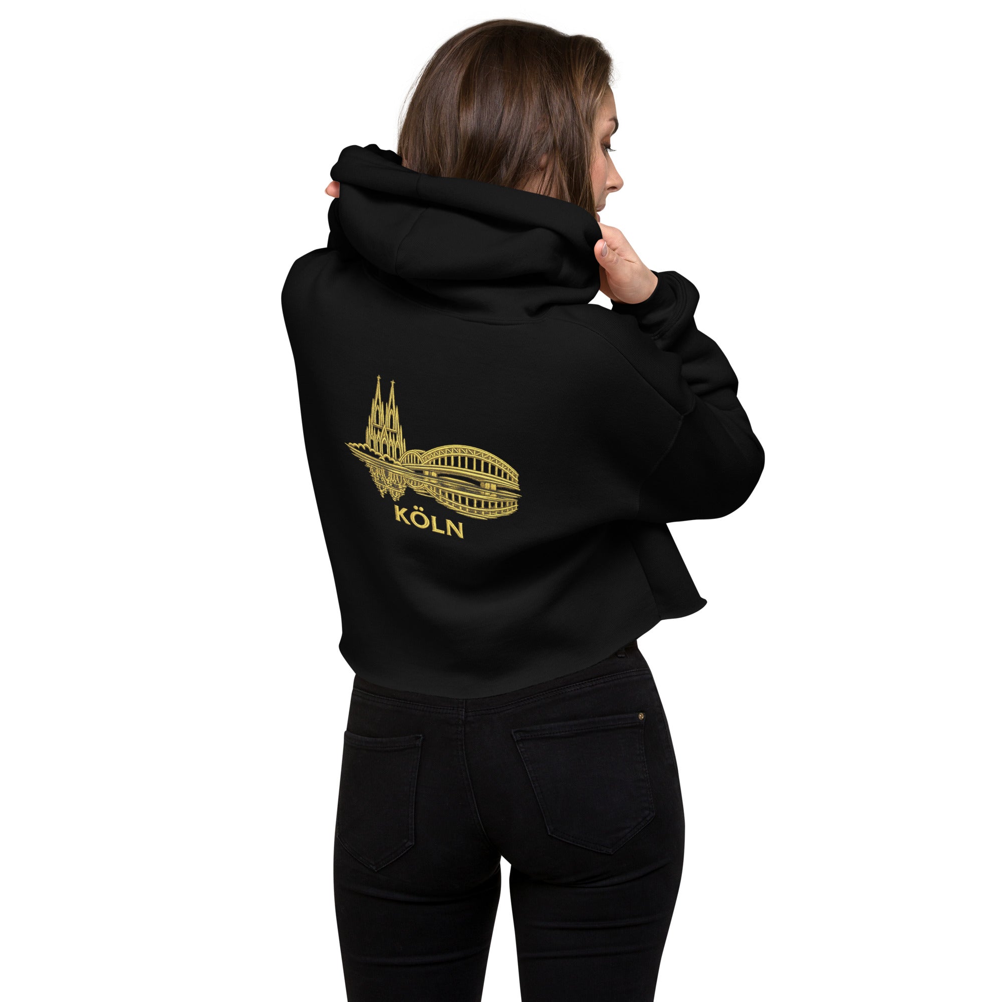 Person wearing a black hoodie with a gold 'Köln' design on the back, standing against a white background.